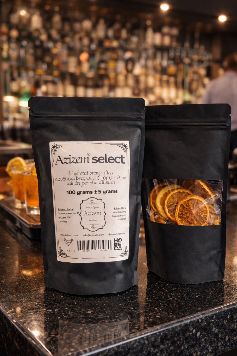 Two black bags labeled 'Azizem Select' on a bar counter with a blurred bar background.